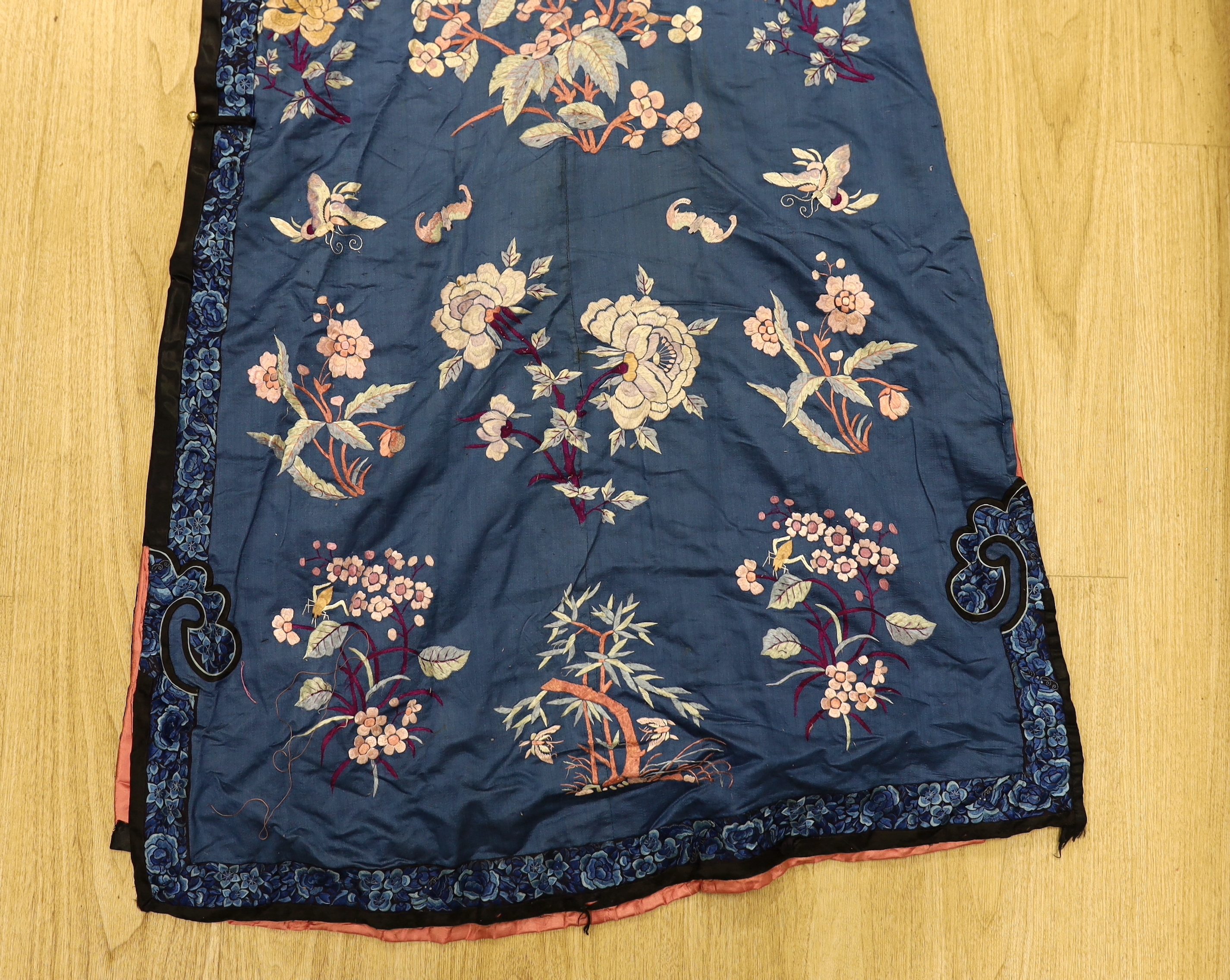 An early 20th century Chinese blue silk embroidered robe, later altered, cut and re-lined, together with various pieces of later Chinese embroidery and an earlier red silk panel with cut velvet circular motifs